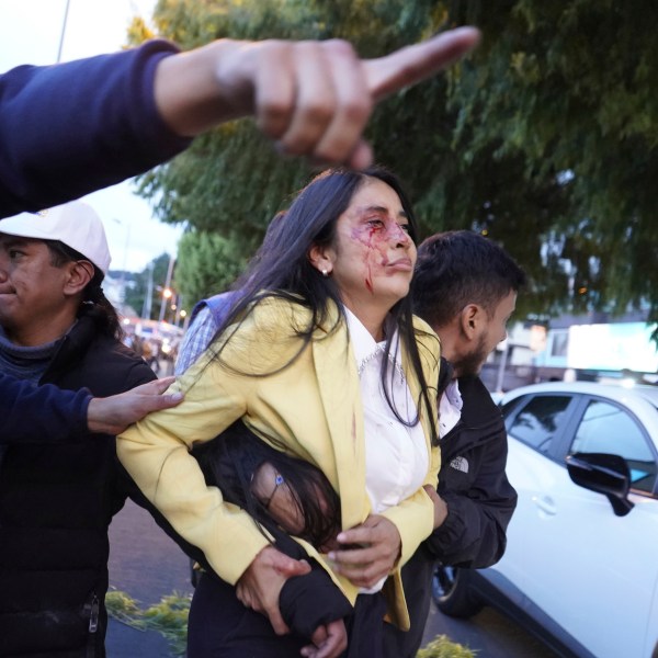 FILE - An injured woman is led away from the scene where presidential candidate Fernando Villavicencio was shot to death at a campaign rally outside a school in Quito, Ecuador, Aug. 9, 2023. Villavicencio, 59, who was known for speaking up against drug cartels, was assassinated less than two weeks before a special presidential election. (API via AP File)