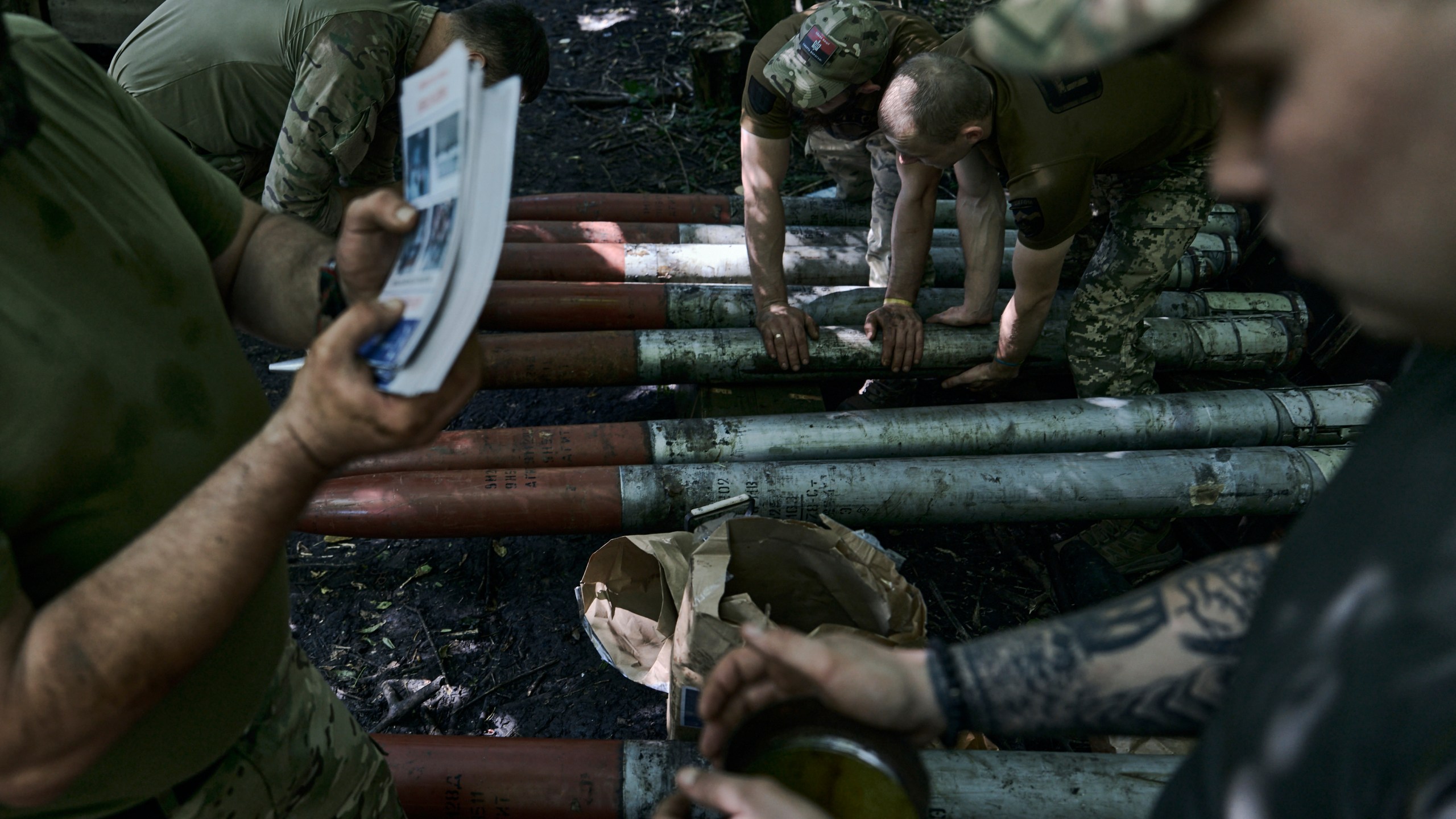Ukrainian soldiers prepare shells with flyers urging the Russian soldiers to surrender to fire toward the Russian positions near Bakhmut, Donetsk region, Ukraine, Sunday, Aug. 13, 2023. (AP Photo/Libkos)